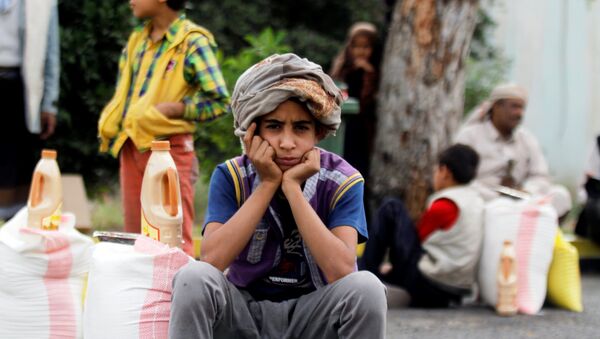 A boy sits next to food supplies he received from a local charity in Sanaa, Yemen, June 23, 2016. - Sputnik International