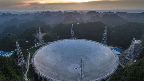 In this photo released by China's Xinhua News Agency, the sun sets above the Five-hundred-meter Aperture Spherical Telescope (FAST) in Pingtang County in southwestern China's Guizhou Province Monday, June 27, 2016 - Sputnik International