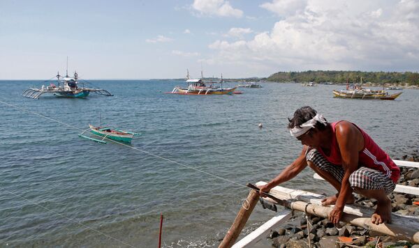 A fisherman repairs his boat overlooking fishing boats that fish in the disputed Scarborough Shoal in the South China Sea, at Masinloc, Zambales, the Philippines (File) A fisherman repairs his boat overlooking fishing boats that fish in the disputed Scarborough Shoal in the South China Sea, at Masinloc, Zambales, the Philippines (File) - Sputnik International