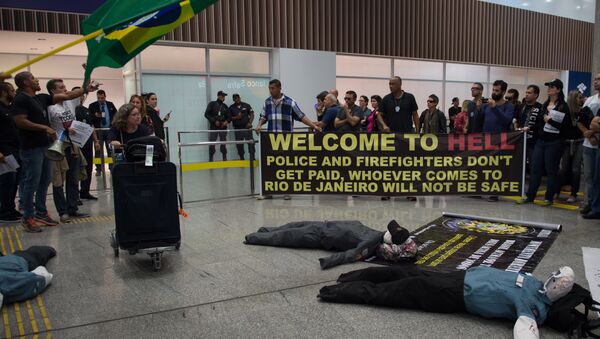 Police officers and firemen welcome passengers with a banner reading Welcome to Hell as they protest against the government for delay in their salary payments at Tom Jobim International Airport in Rio de Janeiro, Brazil, July 4, 2016 - Sputnik International