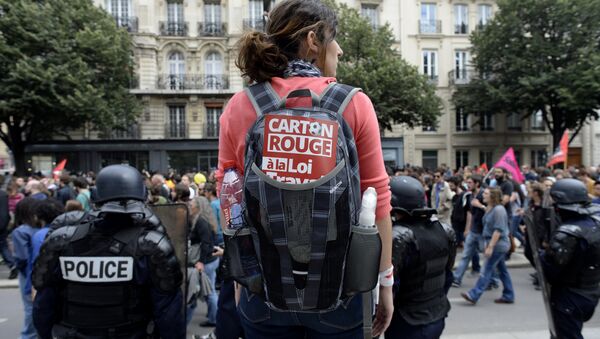 A woman carrying a backpack with a sticker reading Red card to the labour law stands behind French CRS anti-riot police during a demonstration against the government's proposed labour reforms in Paris on July 5, 2016 - Sputnik International