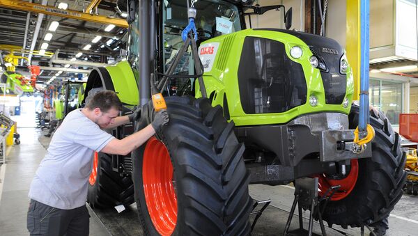 A worker adjusts the front wheel of a tractor on the assembly line of the Claas tractor manufacturer plant (File) - Sputnik International