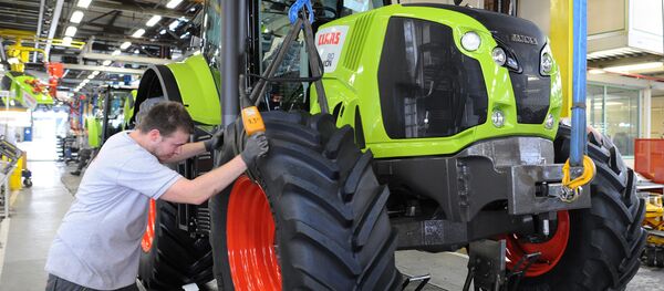 A worker adjusts the front wheel of a tractor on the assembly line of the Claas tractor manufacturer plant (File) - Sputnik International