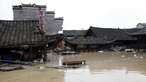 Man standing on the rood of a flood-inundated building in the flooded ancient town of Longshan county, central China's Hunan province - Sputnik International