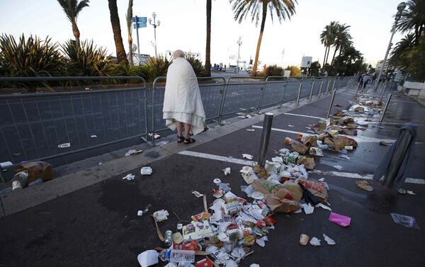 A man walks through debris scatterd on the street the day after a truck ran into a crowd at high speed killing scores celebrating the Bastille Day July 14 national holiday on the Promenade des Anglais in Nice, France, July 15, 2016. - Sputnik International