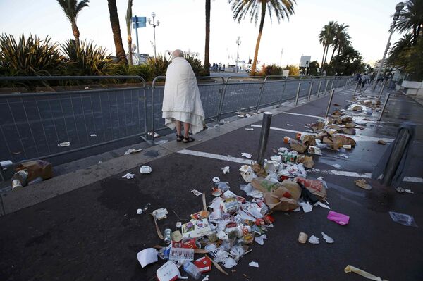 A man walks through debris scatterd on the street the day after a truck ran into a crowd at high speed killing scores celebrating the Bastille Day July 14 national holiday on the Promenade des Anglais in Nice, France, July 15, 2016.  - Sputnik International