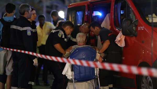 Rescue workers help an injured woman to get in a ambulance on July 15, 2016, after a truck drove into a crowd watching a fireworks display in the French Riviera town of Nice. - Sputnik International