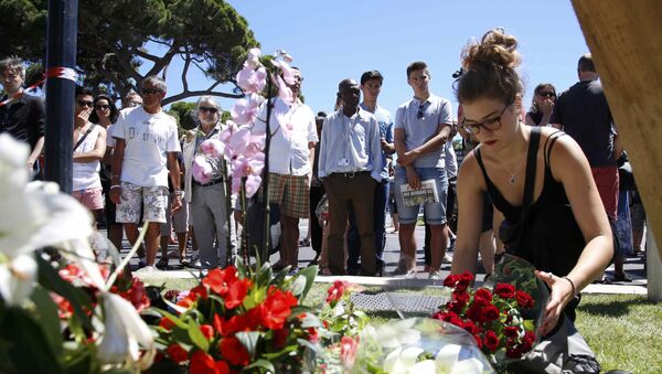 A woman places a bouquet of flowers as people pay tribute near the scene where a truck ran into a crowd at high speed killing scores and injuring more who were celebrating the Bastille Day national holiday, in Nice, France, July 15, 2016. - Sputnik International