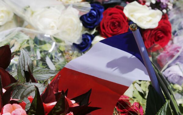 A bouquet of flowers and a French flag is seen as people pay tribute near the scene where a truck ran into a crowd at high speed killing scores and injuring more who were celebrating the Bastille Day national holiday, in Nice, France, July 15, 2016. - Sputnik International