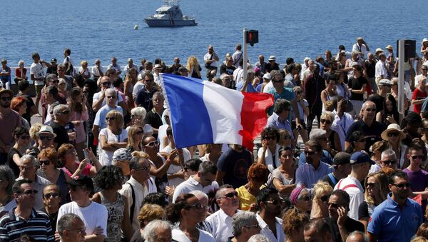 A French flag flies among the crowd as people gather in front of the Monument du Centenaire during a minute of silence on the third day of national mourning to pay tribute to victims of the truck attack along the Promenade des Anglais on Bastille Day that killed scores and injured as many in Nice, France, July 18, 2016. - Sputnik International