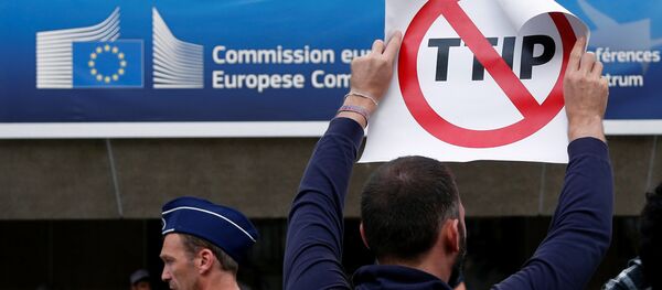 A demonstrator holds a sign during a protest outside a congress centre where negotiators are expected to discuss the 14th Round of the Transatlantic Trade and Investment Partnership (TTIP) in Brussels, Belgium, July 12, 2016. A demonstrator holds a sign during a protest outside a congress centre where negotiators are expected to discuss the 14th Round of the Transatlantic Trade and Investment Partnership (TTIP) in Brussels, Belgium, July 12, 2016. - Sputnik International