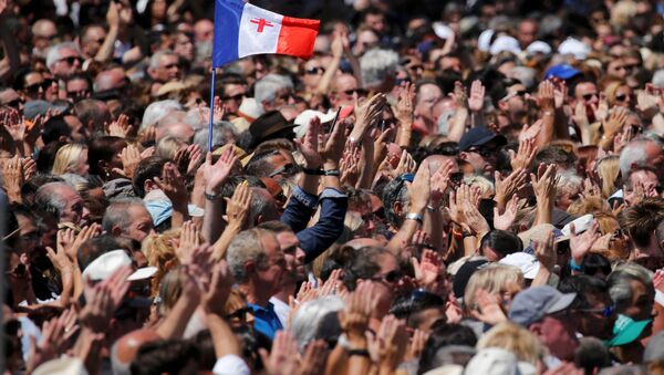 A French flag flies among the crowd as people applaud in front of the Monument du Centenaire during a minute of silence on the third day of national mourning to pay tribute to victims of the truck attack along the Promenade des Anglais on Bastille Day that killed scores and injured as many in Nice, France, July 18, 2016. - Sputnik International