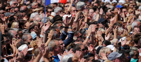 A French flag flies among the crowd as people applaud in front of the Monument du Centenaire during a minute of silence on the third day of national mourning to pay tribute to victims of the truck attack along the Promenade des Anglais on Bastille Day that killed scores and injured as many in Nice, France, July 18, 2016. - Sputnik International