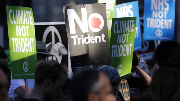 Demonstrators hold placards calling for government funds to be spent on the NHS and climate change, as they attend an anti-war and anti-trident demonstration near the Houses of Parliament in central London on July 18, 2016 - Sputnik International
