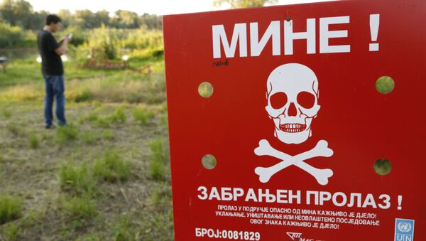 A Bosnian man plays the Pokemon game on his phone as he stands near a sign warning of a Minefield, near the Bosnian town of Brcko, on Tuesday, July 19, 2016 - Sputnik International