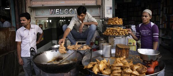 In this Tuesday, Nov. 12, 2013 photo, a cook uses his hand to release pieces of chicken into hot oil at a street side food joint in New Delhi, India - Sputnik International