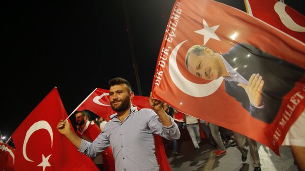 A pro-government supporter waves a Turkish flag and one with the picture of Turkey's President Recep Tayyip Erdogan, right, during a rally on the road leading to Istanbul's iconic Bosporus Bridge, Thursday, July 21, 2016 - Sputnik International