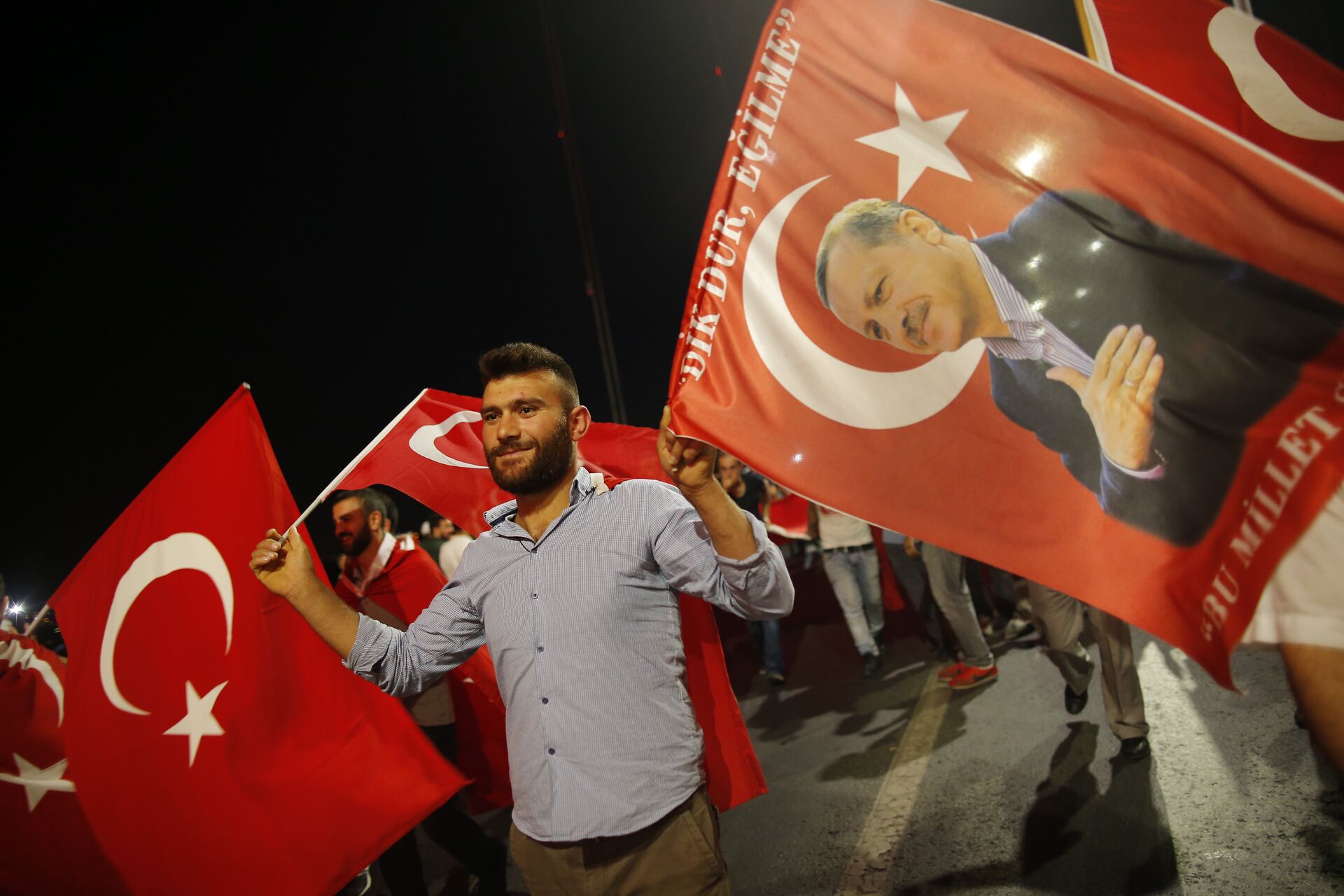 A pro-government supporter waves a Turkish flag and one with the picture of Turkey's President Recep Tayyip Erdogan, right, during a rally on the road leading to Istanbul's iconic Bosporus Bridge, Thursday, July 21, 2016 - Sputnik International, 1920, 25.08.2022