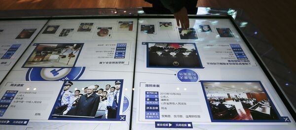 A visitor, top, looks at an electronic screen displaying images and convicted corruption charges of China's fallen politicians, Bo Xilai, bottom second right, Zhou Yongkang, bottom left, and other senior officials, at the China Court Museum in Beijing, Tuesday, Jan. 12, 2016 - Sputnik International