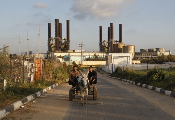 Palestinians ride a donkey-pulled cart past Gaza's sole power plant in Nusairat Palestinians ride a donkey-pulled cart past Gaza's sole power plant in Nusairat - Sputnik International