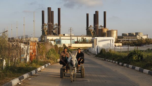 Palestinians ride a donkey-pulled cart past Gaza's sole power plant in Nusairat - Sputnik International