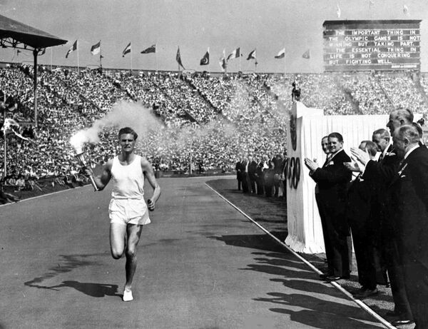 British athlete John Mark holds the Olympic Flame aloft as he makes his circuit of the Olympic track during the opening ceremony of the XIV Olympiad, in Wembley Stadium, London, July 29, 1948. (File) - Sputnik International