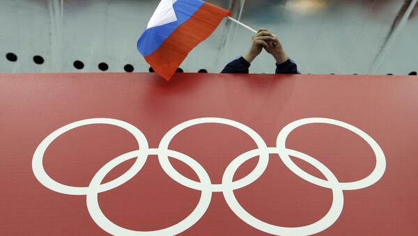 Russian skating fan holds the country's national flag over the Olympic rings before the start of the men's 10,000-meter speedskating race at Adler Arena Skating Center during the 2014 Winter Olympics in Sochi, Russia. (File) - Sputnik International