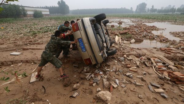 People push a car turned over during floods in Xingtai, Hebei Province, China, July, 24, 2016.  - Sputnik International