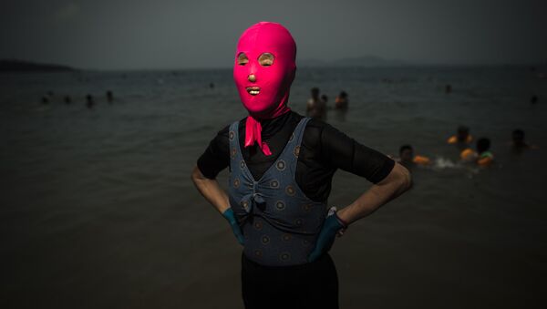 A woman wearing a facekini poses at the beach in Qingdao, eastern China's Shandong province - Sputnik International