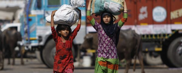 Indian child laborers carry sacks of vegetable leftovers collected from a wholesale market to be sold in their shantytown, on the World Day against Child Labor, on the outskirts of Jammu, India (File) - Sputnik International