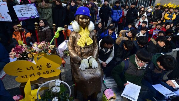 South Korean students sit near a statue (C) of a teenage girl symbolizing former comfort women who served as sex slaves for Japanese soldiers during World War II, during a weekly anti-Japanese demonstration in front of the Japanese embassy in Seoul (File) - Sputnik International