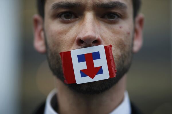A former Bernie Sanders delegate wears a Hillary Clinton presidential campaign sticker over his mouth as he protests during the third session at the Democratic National Convention in Philadelphia, Pennsylvania, U.S. July 27, 2016. A former Bernie Sanders delegate wears a Hillary Clinton presidential campaign sticker over his mouth as he protests during the third session at the Democratic National Convention in Philadelphia, Pennsylvania, U.S. July 27, 2016. - Sputnik International