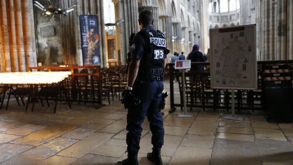 A policeman stands guard while people arrive for a Mass at the Rouen Cathedral, on July 27, 2016 in Rouen, to pay tribute to the priest Jacques Hamel, killed on July 26 in a church of Saint-Etienne-du-Rouvray during a hostage-taking claimed by Islamic State group - Sputnik International