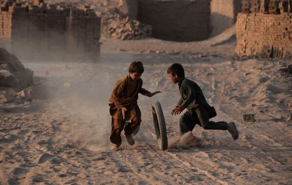 Афганские дети играют с шиной на пыльной дороге на окраине Джелалабада - Sputnik International