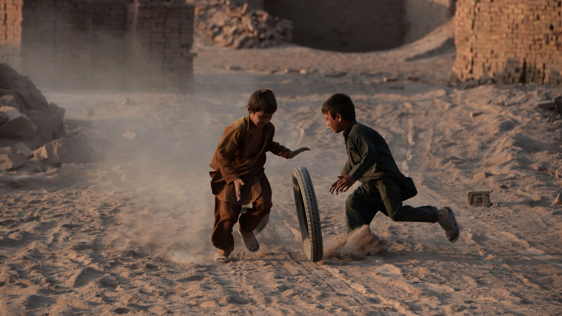 Афганские дети играют с шиной на пыльной дороге на окраине Джелалабада - Sputnik International, 1920, 15.12.2021