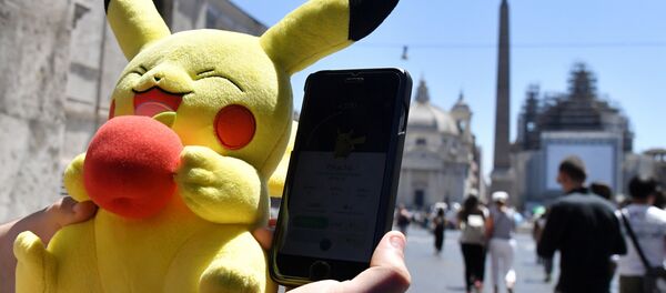 A gamer holds a Pokemon mascot and his mobile phone as he plays with the Pokemon Go application in central Rome on July 19, 2016 A gamer holds a Pokemon mascot and his mobile phone as he plays with the Pokemon Go application in central Rome on July 19, 2016 - Sputnik International