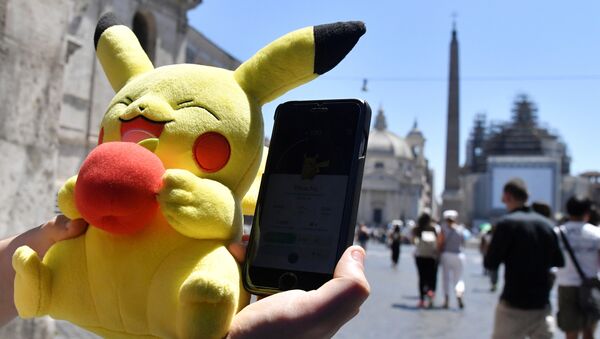 A gamer holds a Pokemon mascot and his mobile phone as he plays with the Pokemon Go application in central Rome on July 19, 2016 - Sputnik International