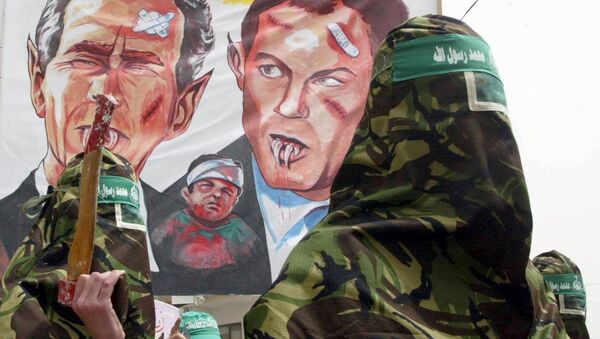 Masked Palestinian members of the Islamic militant group Hamas, march with a larger banner showing a fanged US President George W. Bush (L) and a similar depiction of British Prime Minister Tony Blair during an anti-war protest in the Nusairat refugee camp 04 April 2003, in the Gaza Strip. - Sputnik International