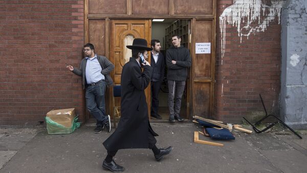 An Orthodox jew talks on his mobile phone as he walks past the Ahavas Torah synagogue in the Stamford Hill area of north London on March 22, 2015 - Sputnik International