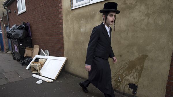 An Orthodox jew walks past a damaged door belonging to the Ahavas Torah synagogue in the Stamford Hill area of north London on March 22, 2015 - Sputnik International