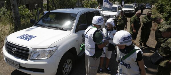 Members of the Organization for Security and Co-operation in Europe (OSCE) stand in the village of Shyrokyne, Donetsk region on July 4, 2015 - Sputnik International
