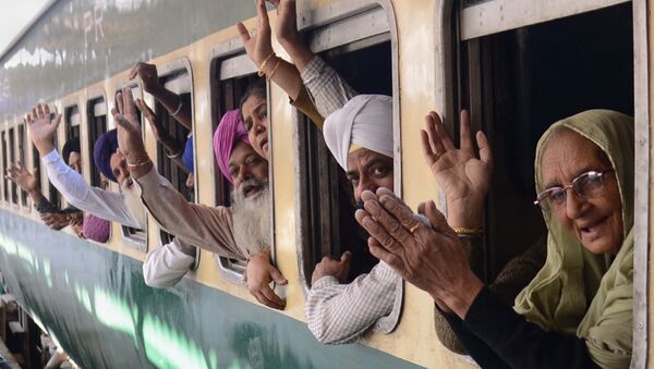 Indian Sikh pilgrims pose for a photograph as they wave from a train bound for Pakistan at a railway station in Amritsar on November 15, 2013 - Sputnik International