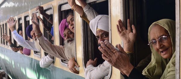 Indian Sikh pilgrims pose for a photograph as they wave from a train bound for Pakistan at a railway station in Amritsar on November 15, 2013 - Sputnik International