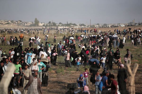 In this June 14, 2015 file photo taken from the Turkish side of the border between Turkey and Syria, in Akcakale, Sanliurfa province, southeastern Turkey, thousands of Syrian refugees walk in order to cross into Turkey In this June 14, 2015 file photo taken from the Turkish side of the border between Turkey and Syria, in Akcakale, Sanliurfa province, southeastern Turkey, thousands of Syrian refugees walk in order to cross into Turkey - Sputnik International