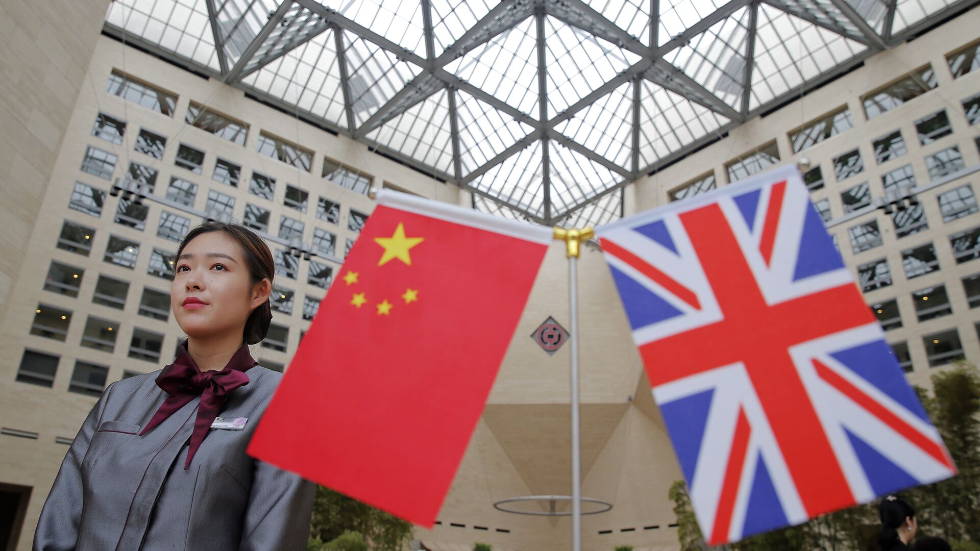 A member of staff stands behind flags as officials arrive for the UK-China High Level Financial Services Roundtable at the Bank of China head office building in Beijing on July 22, 2016 - Sputnik International, 1920, 03.02.2021