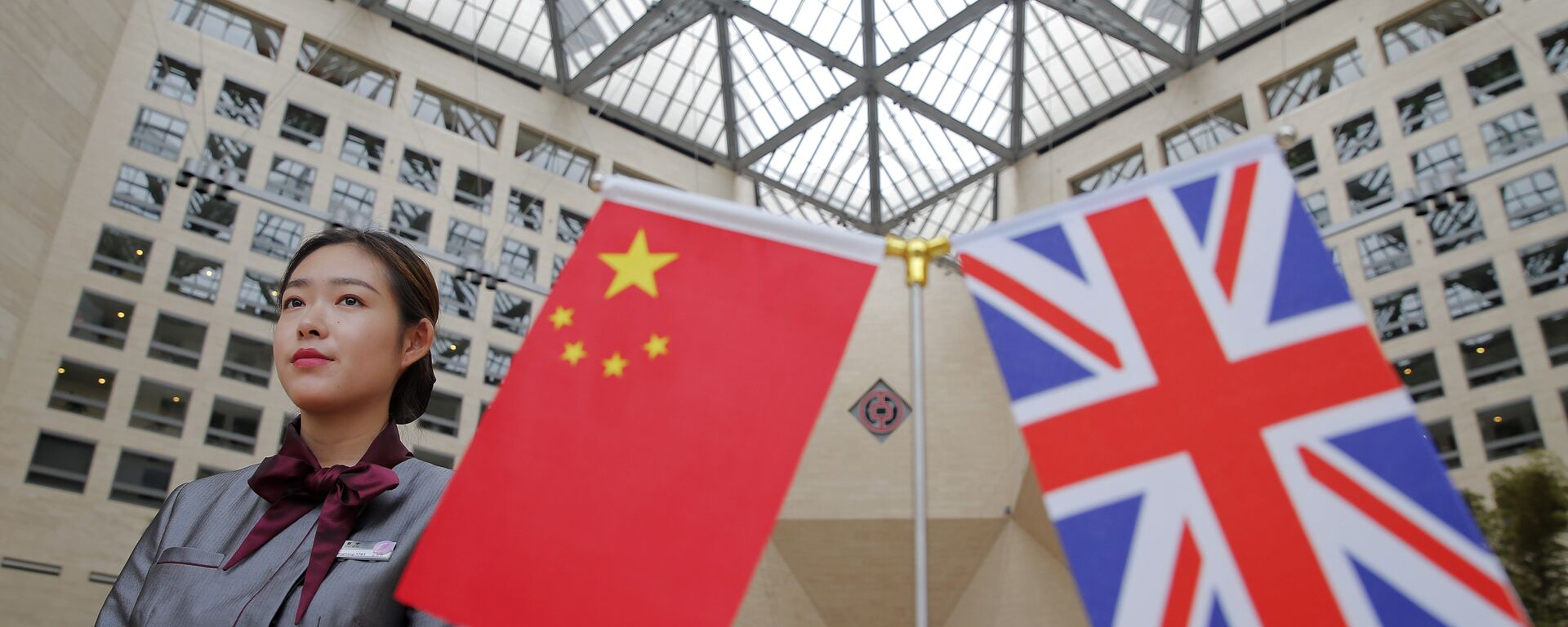 A member of staff stands behind flags as officials arrive for the UK-China High Level Financial Services Roundtable at the Bank of China head office building in Beijing on July 22, 2016 - Sputnik International, 1920, 03.02.2021