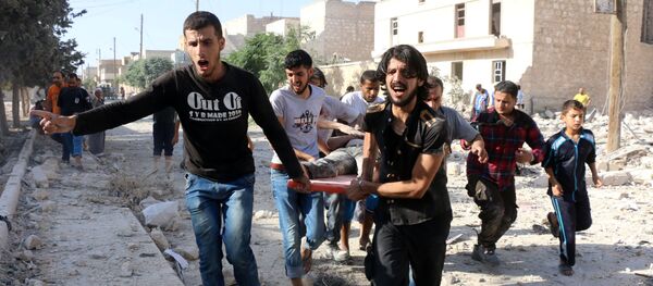 Syrians carry a stretcher as they evacuate victims from the rubble of a collapsed building following a reported air strike on the rebel-held neighbourhood of Sakhur in the northern city of Aleppo on July 19, 2016 - Sputnik International