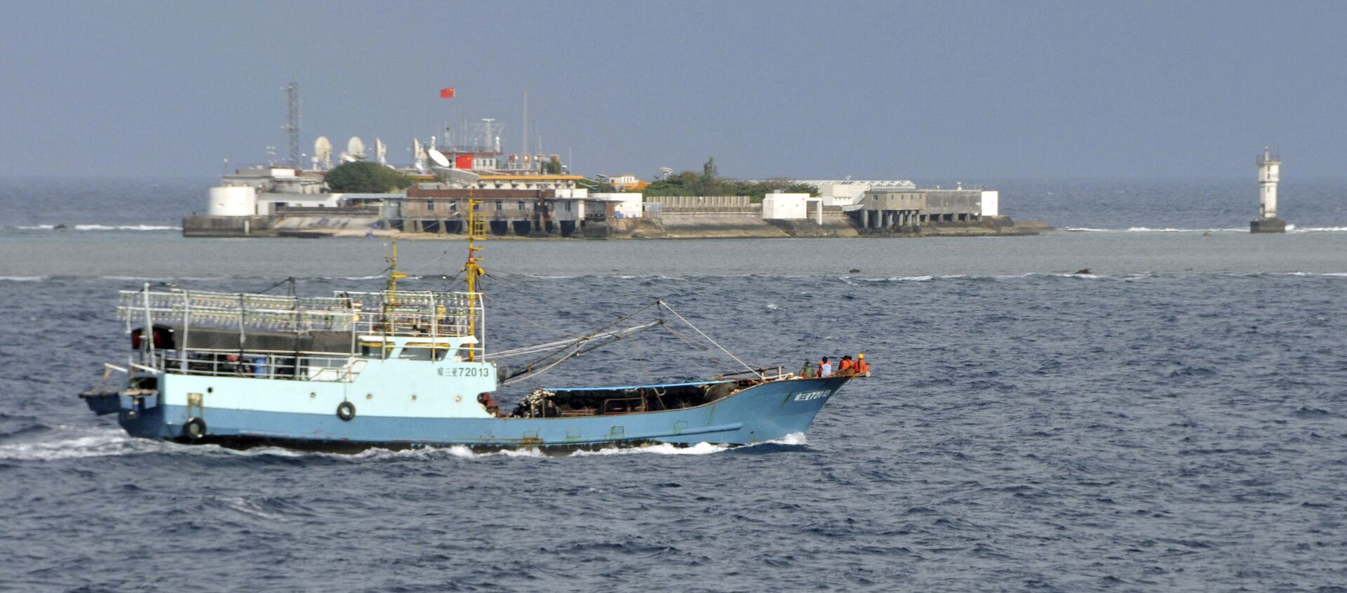 Chinese fishing vessel sails by Fiery Cross Reef, background, also known as Yongshu Reef, of the Spratly Islands in South China Sea. File photo. - Sputnik International, 1920, 23.03.2021