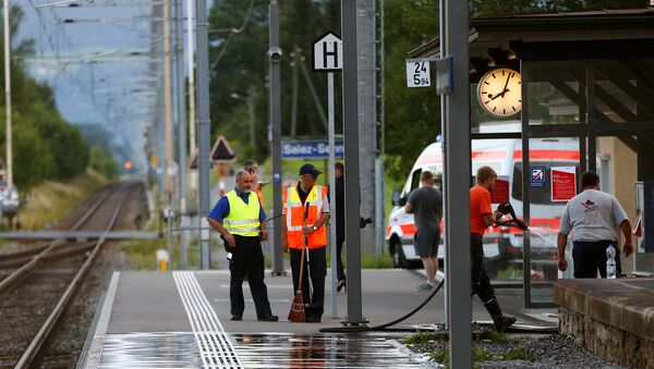 A Swiss police officer stands near workers cleaning a platform after a 27-year-old Swiss man's attack on a Swiss train at the railway station in the town of Salez, Switzerland August 13, 2016 - Sputnik International
