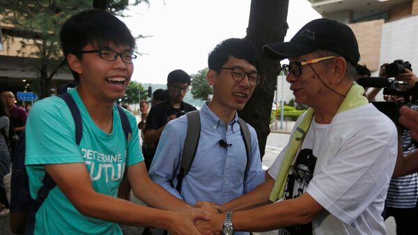 Student leaders Joshua Wong (L) and Nathan Law (C) are greeted by a supporter after a verdict, on charges of inciting and participating in an illegal assembly in 2014 which led to the Occupy Central pro-democracy movement, outside a court in Hong Kong August 15, 2016 - Sputnik International